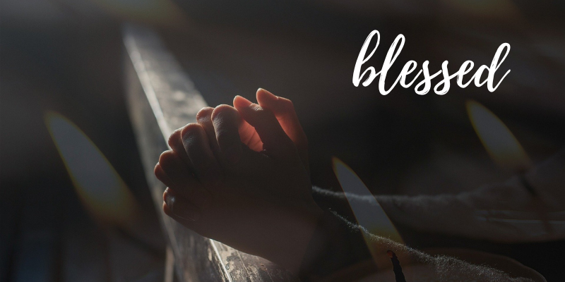Decorative photo of praying  hands with the word "blessed."