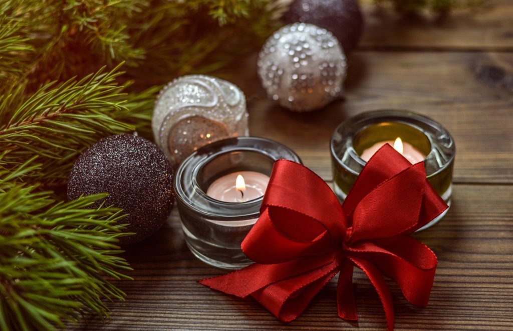 Decorative Christmas picture with greenery, small candles burning, and red bow