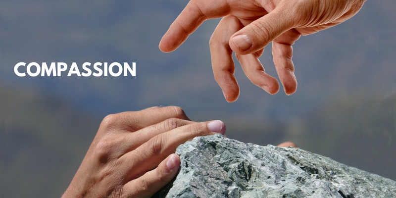 Hand reaching out in compassion to another climbing a difficult rock-scape