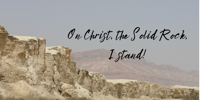Israel in the background, rocky  ground, with the words, On  Christ, the Solid Rock, I stand.