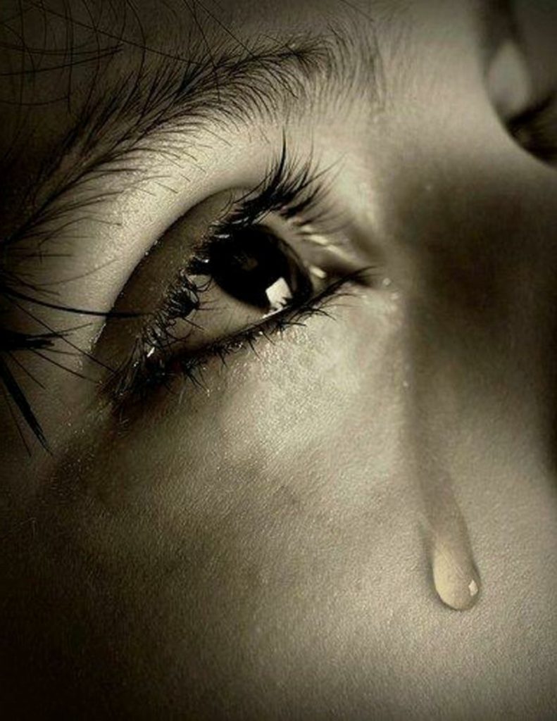 A picture of a human eye, tears falling the eye - represents suffering