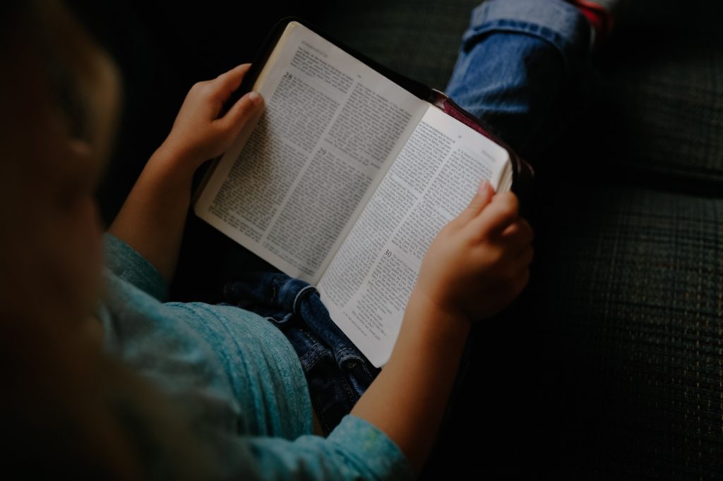 Picture of a girl reading the Word of God, the Bible.