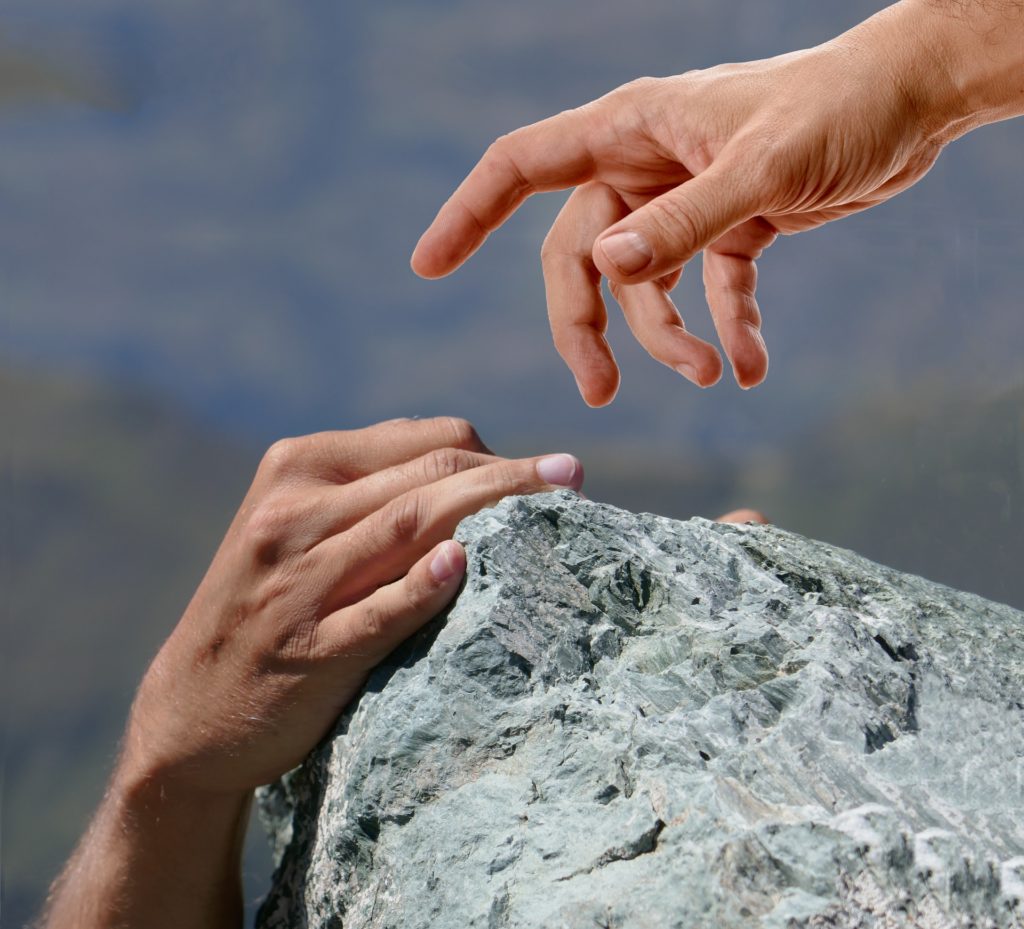 Picture of a hand on a rock, and another hand reaching out to help ... doing good